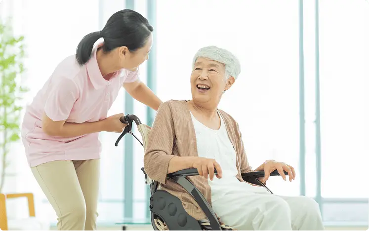 車椅子に乗っている高齢の女性とその車椅子を推している女性